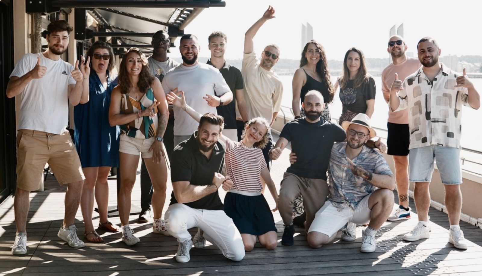 Photo de groupe sur un rooftop au soleil, les participants lèvent les bras.